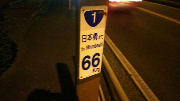 夜の国道一号に立つ標識。「日本橋まで66km」。