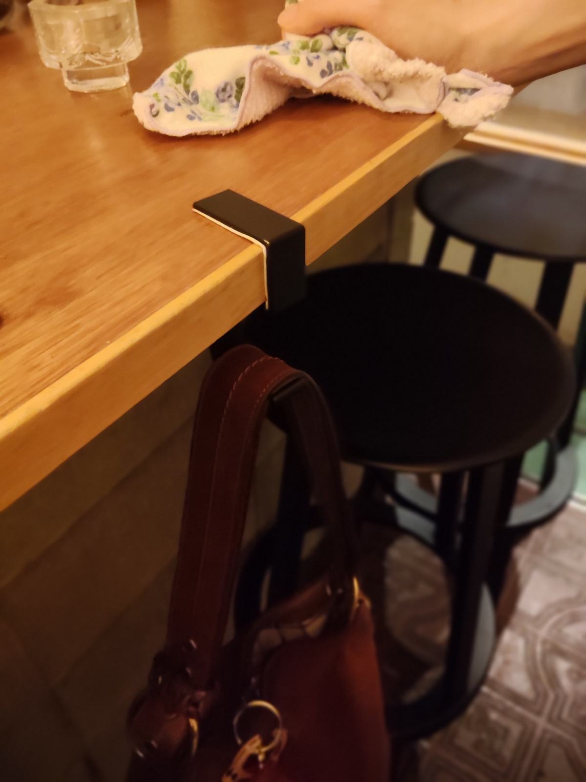 カウンターの縁に留めた黒い荷物かけの金具に、赤茶の革の鞄が掛かっている。