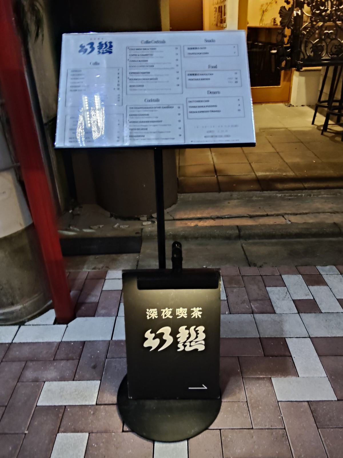 新道通りの歩道に出た立て看板と、その奥に立つ黒い品書きの板。夜の店先の灯りに照らされている。