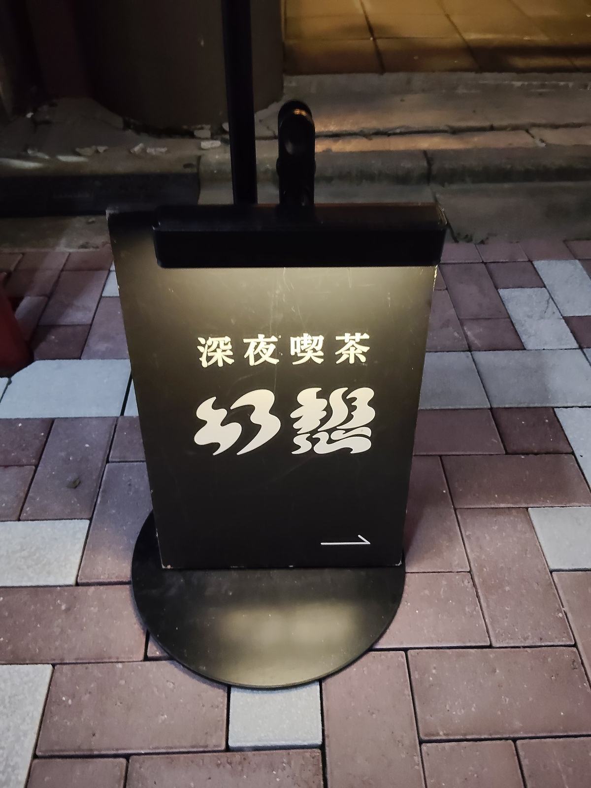 日本橋馬喰町、新道通りの歩道に立つ「深夜喫茶 幻想」の黒い立て看板。白い字の店名と矢印、足元は赤茶と白のタイル。