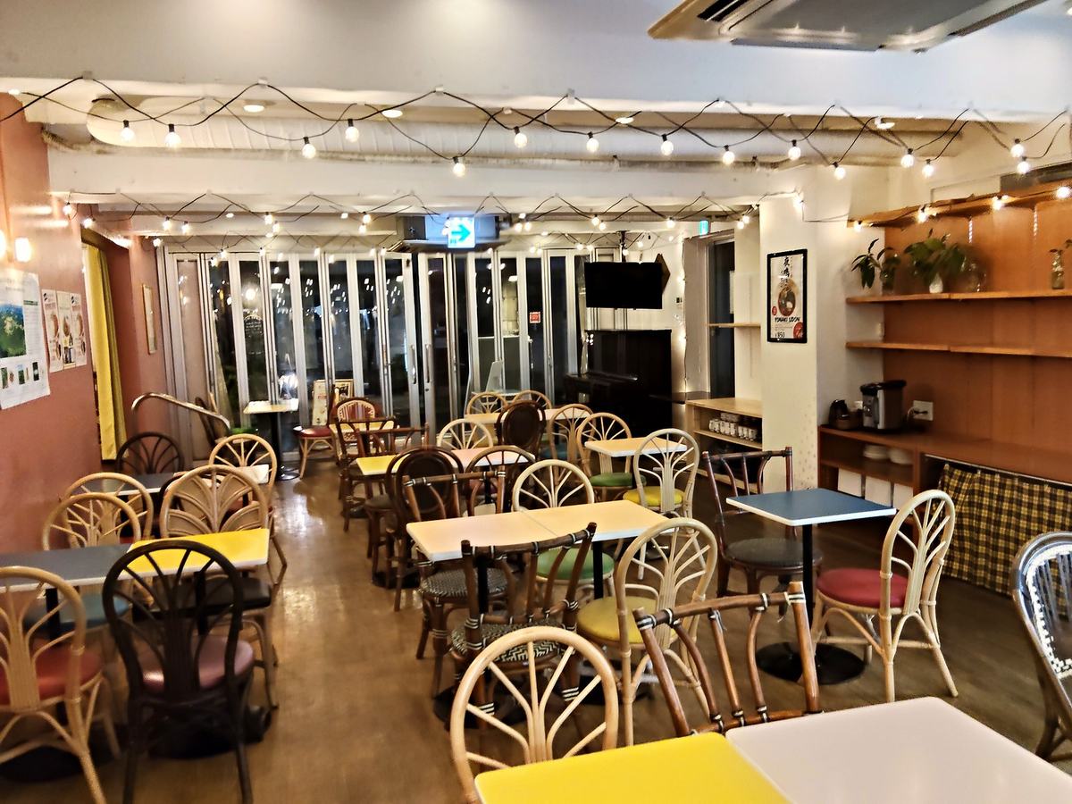深夜2時のサクラカフェ店内。電球の連なる天井と、色のばらばらな椅子。