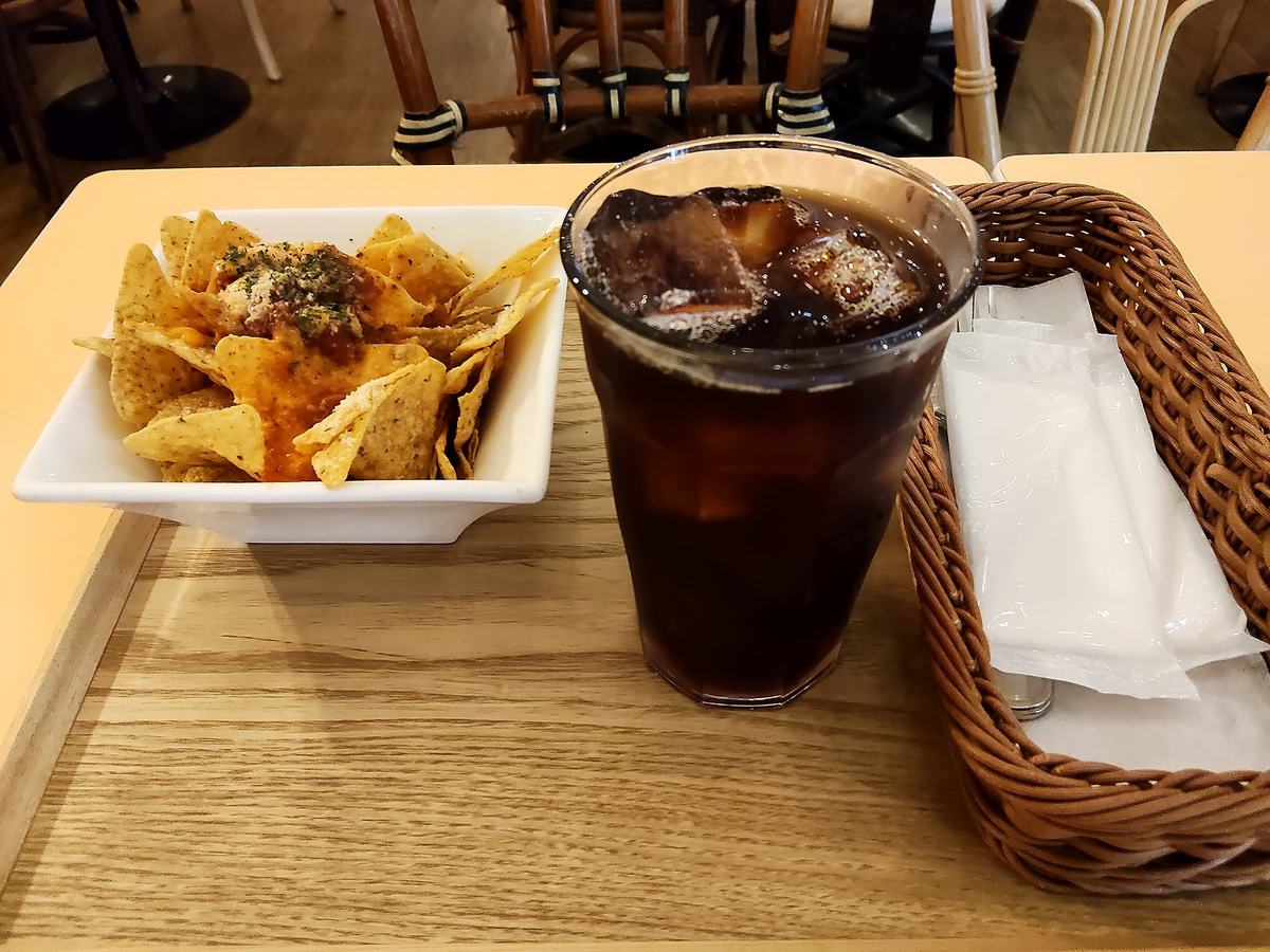 スパイシーチーズナチョスとアイスコーヒーがテーブルに置かれている。