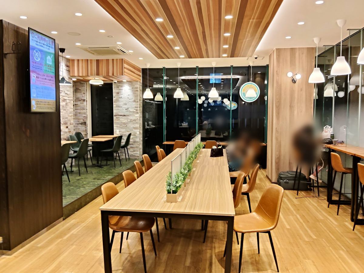 深夜4時前のスマートカフェ店内。木目の内装に暖色の照明。席にいる人はぼかされている。