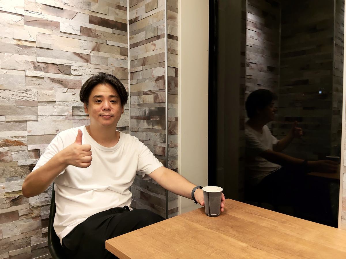 スマートカフェ秋葉原の席で一息つく筆者・池森裕毅。テーブルの上にアイスコーヒー。