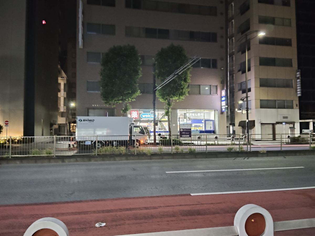 深夜の神田小川町。閉まった店が並ぶ通りで、ウエルシアの明かりだけが白く灯っている