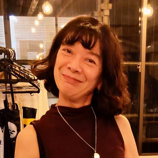 紺の壁の前で微笑む香織さん。
