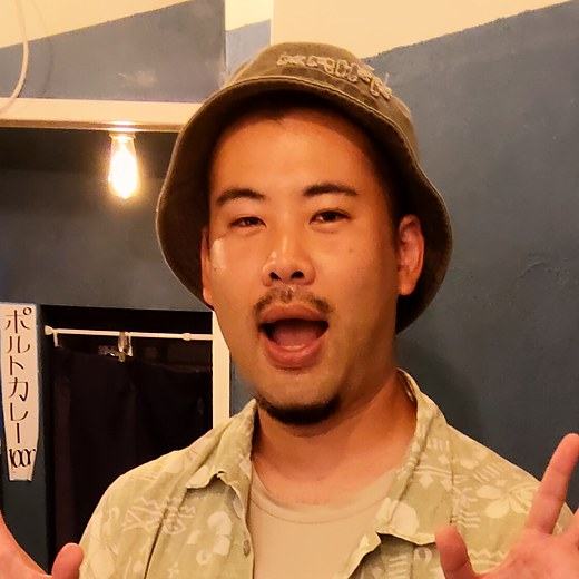 バケットハットをかぶって両手を広げ、笑っている喜屋武さん。