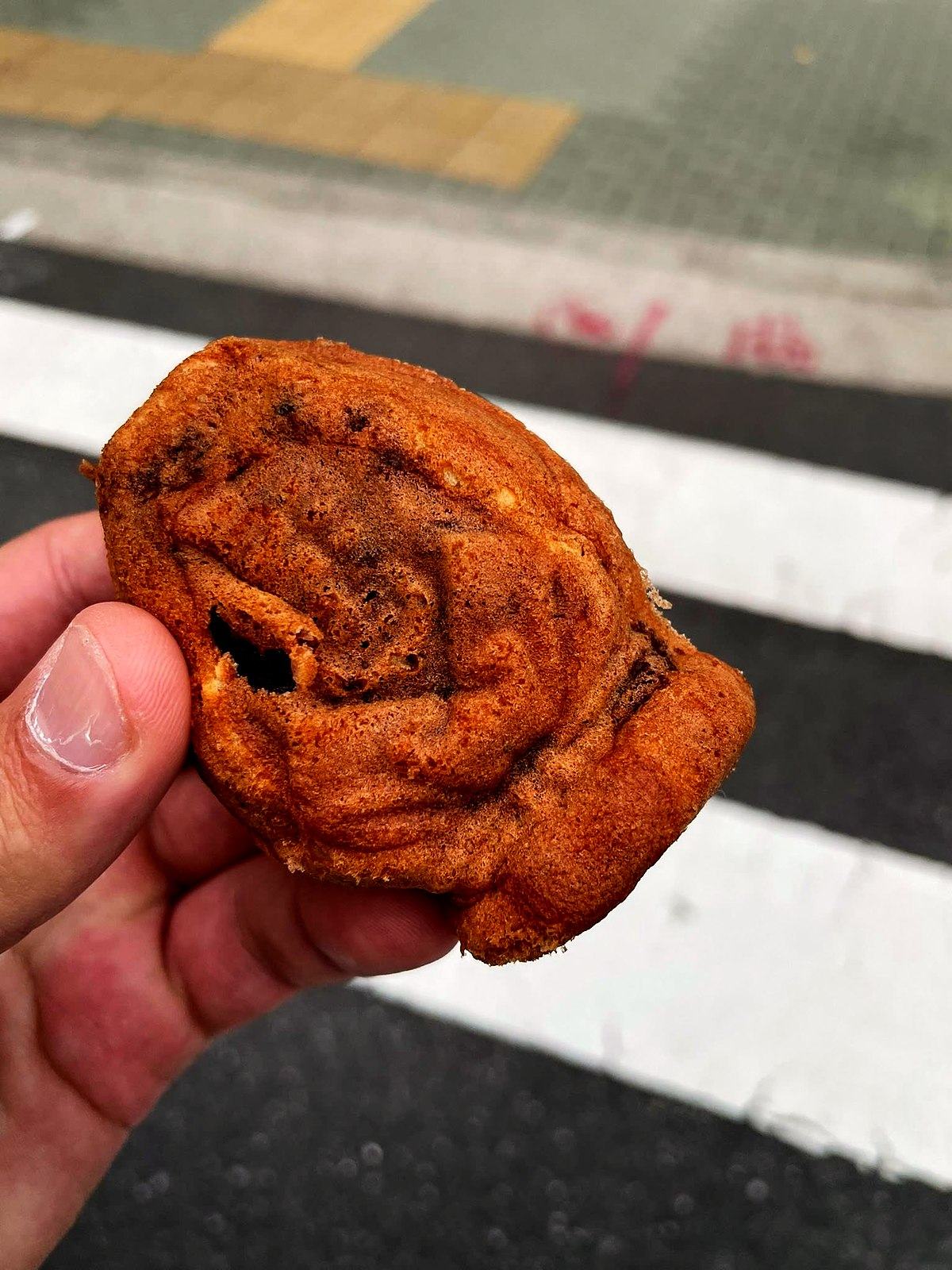手に持った人形焼のクローズアップ。横断歩道の上で。