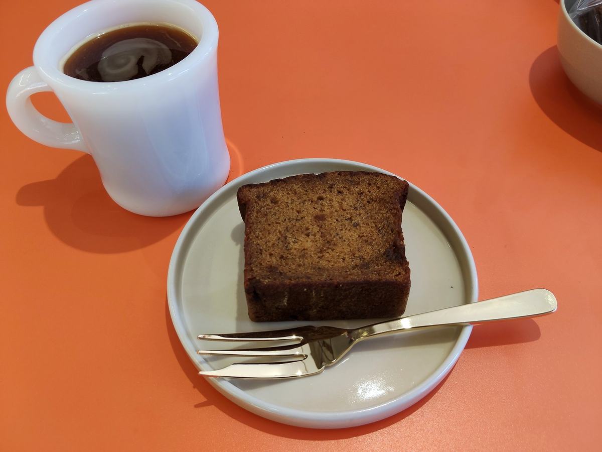 白いマグのハウスブレンドと、ケーキの皿。