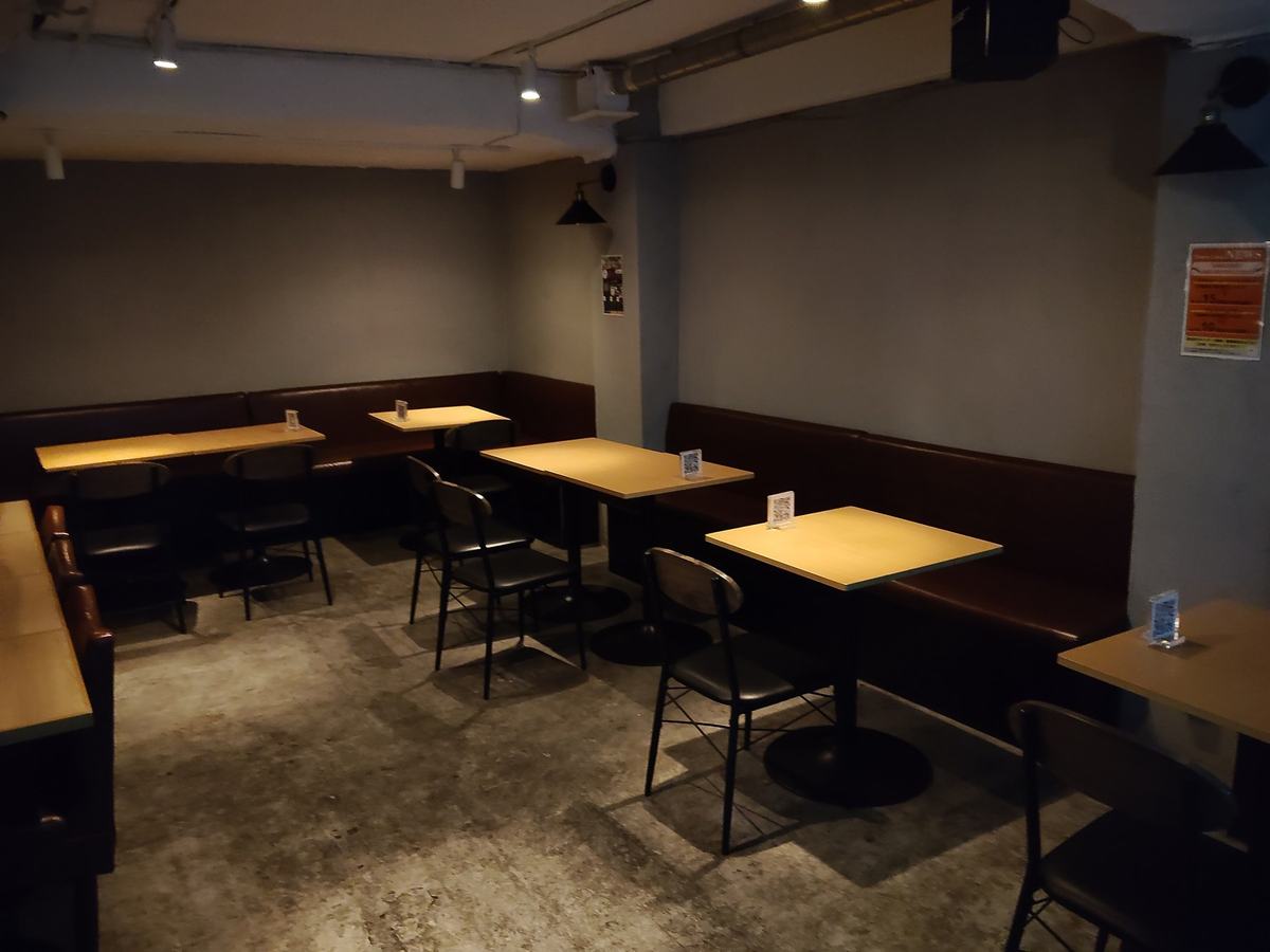 奥の空間。壁沿いの革張りのベンチシートと、木の天板のテーブルがいくつも並ぶ。天井の照明は落としてある。