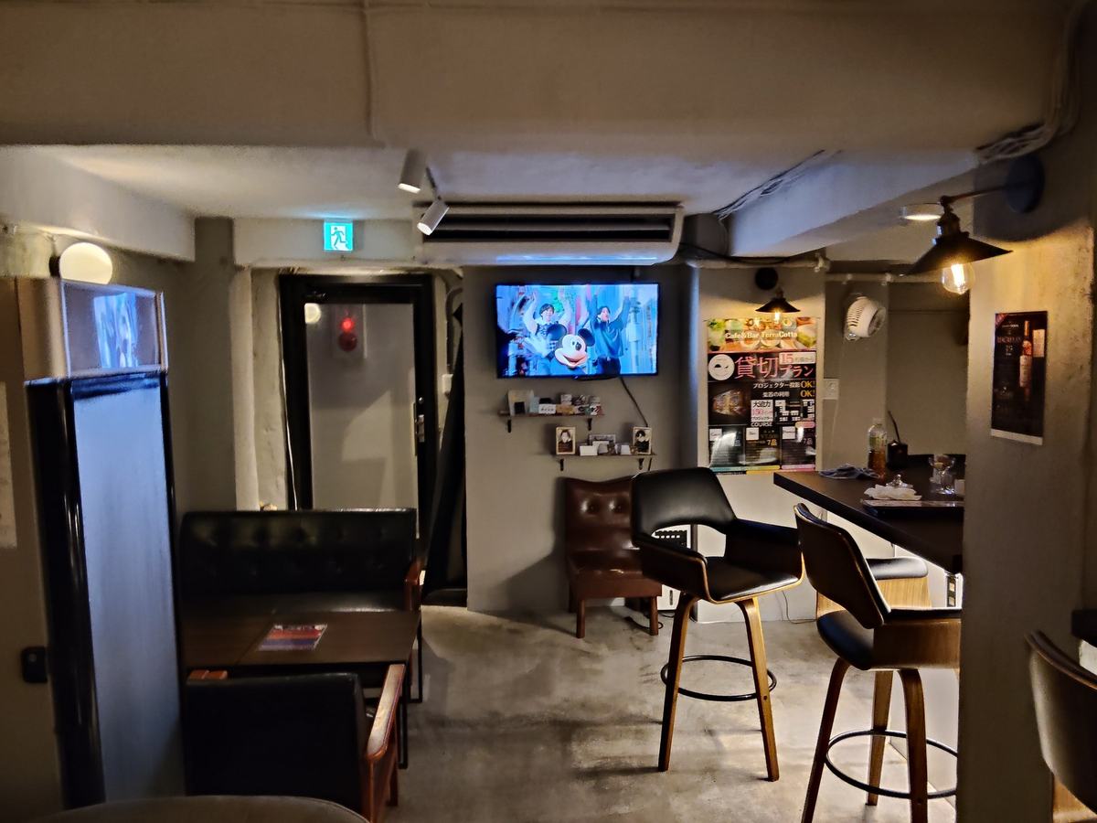 バー側のカウンターとスツール。客のいない深夜、棚の照明だけが灯っている。