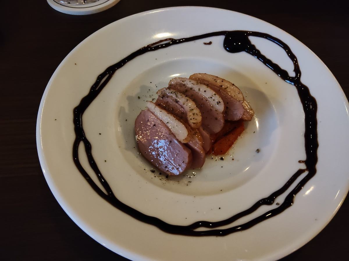 白い皿に盛られた鴨のロースト。薄切りの肉の下にバルサミコのソースが敷いてある。