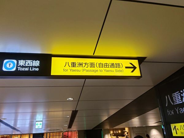 黄色い案内サイン「八重洲方面（自由通路）」。地下通路の天井に下がっている。