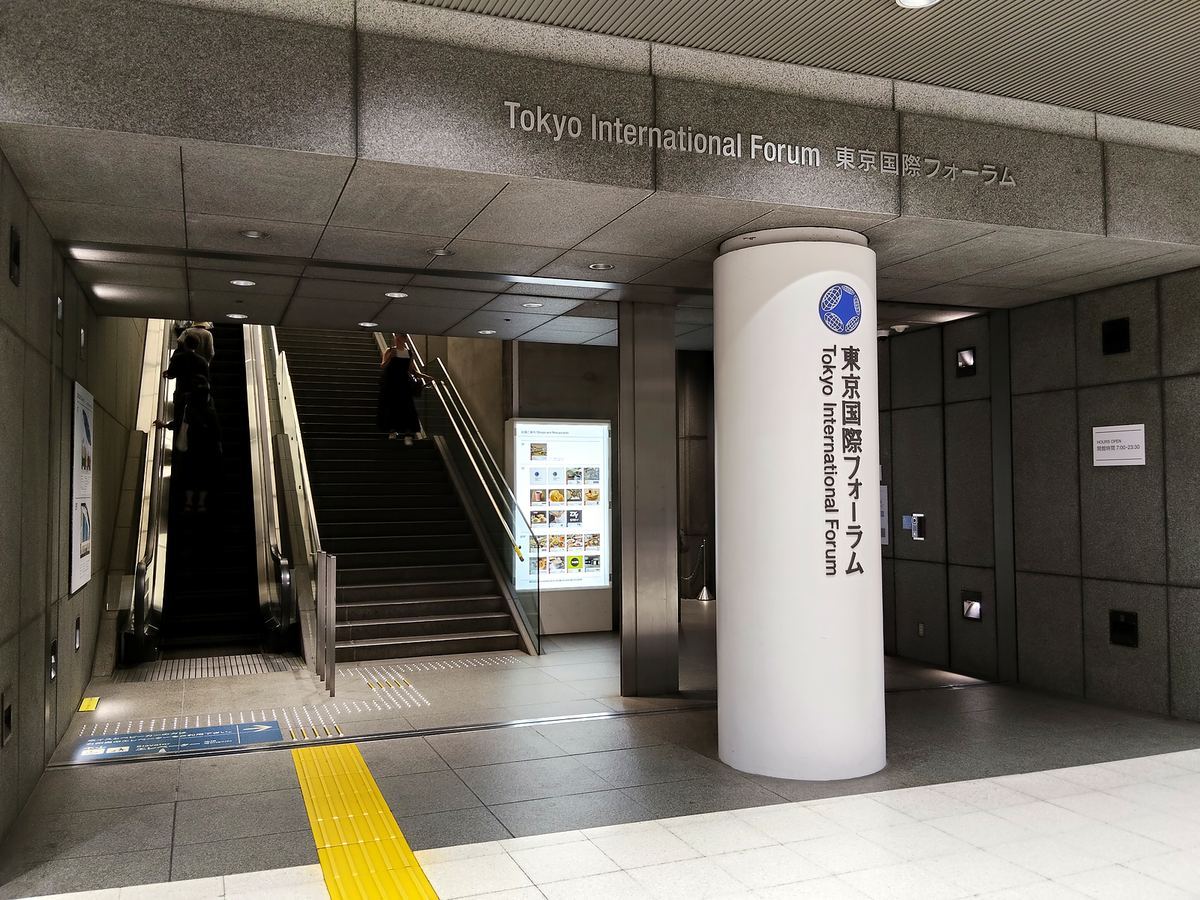 東京国際フォーラムの地下入口。丸い柱に施設名が縦書きで入り、奥に上りのエスカレーターが見える。